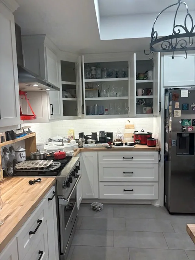 Kitchen cabinets open and full of glassware, counters covered
