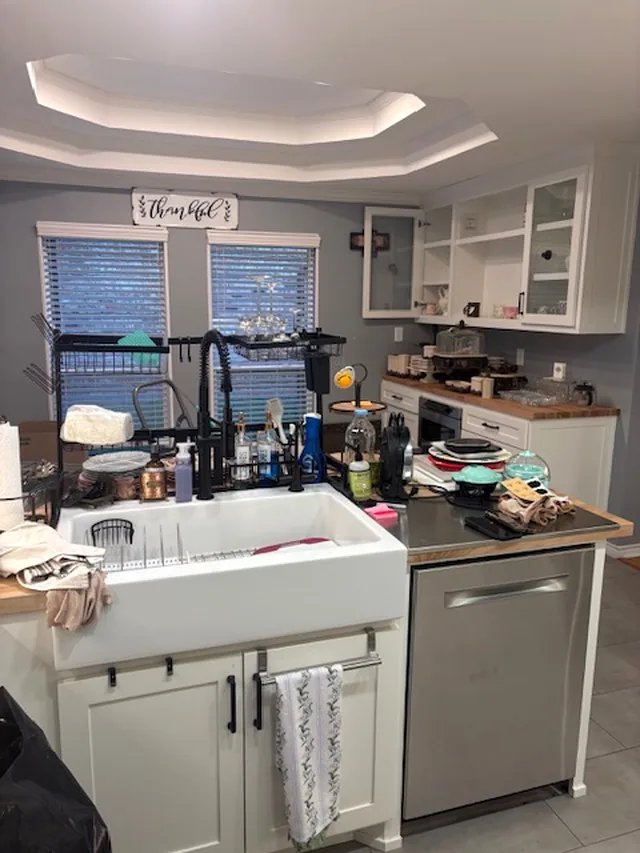 The farmhouse sink area of the kitchen, cluttered