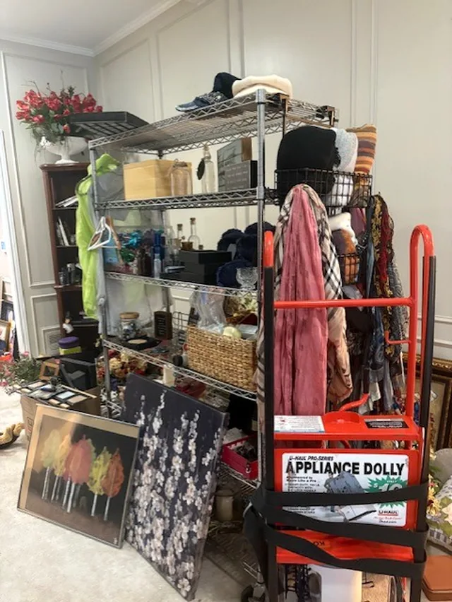 A wire shelf of scarves, canvases and a dolly in the living room