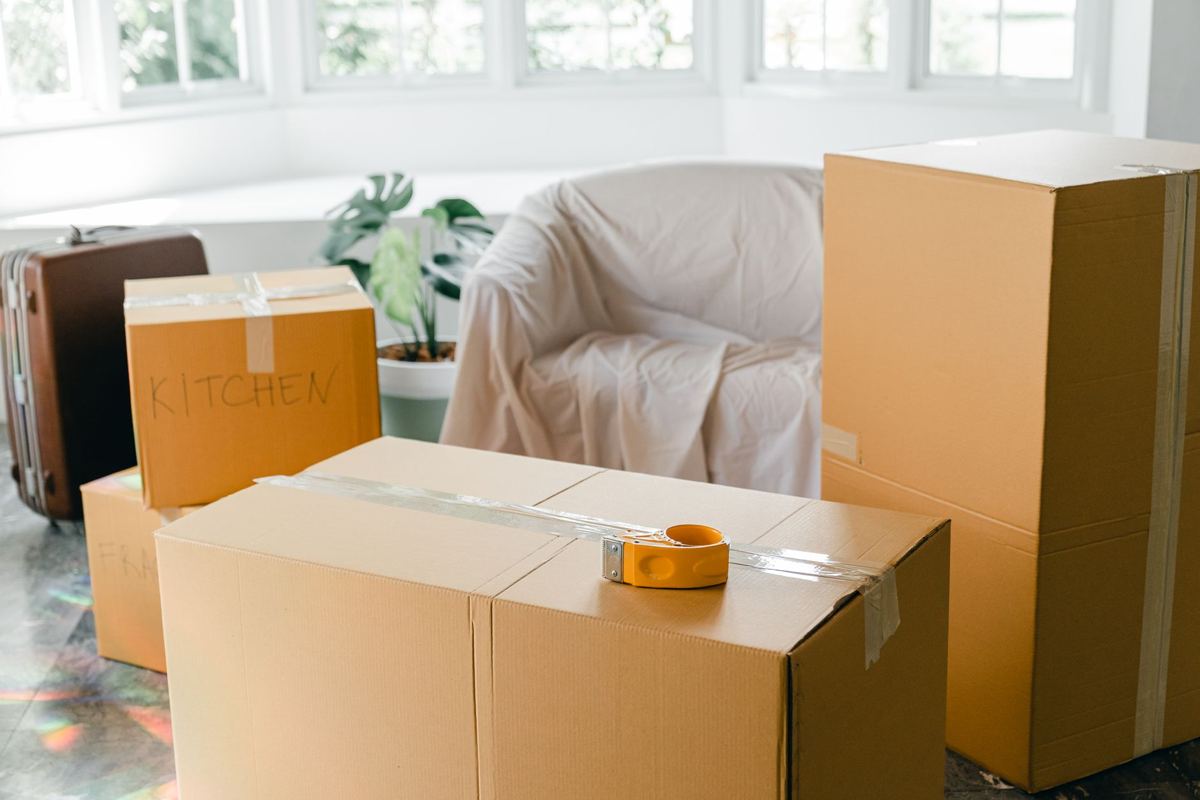 Taped moving boxes and a sheet-covered armchair in an emptied living room