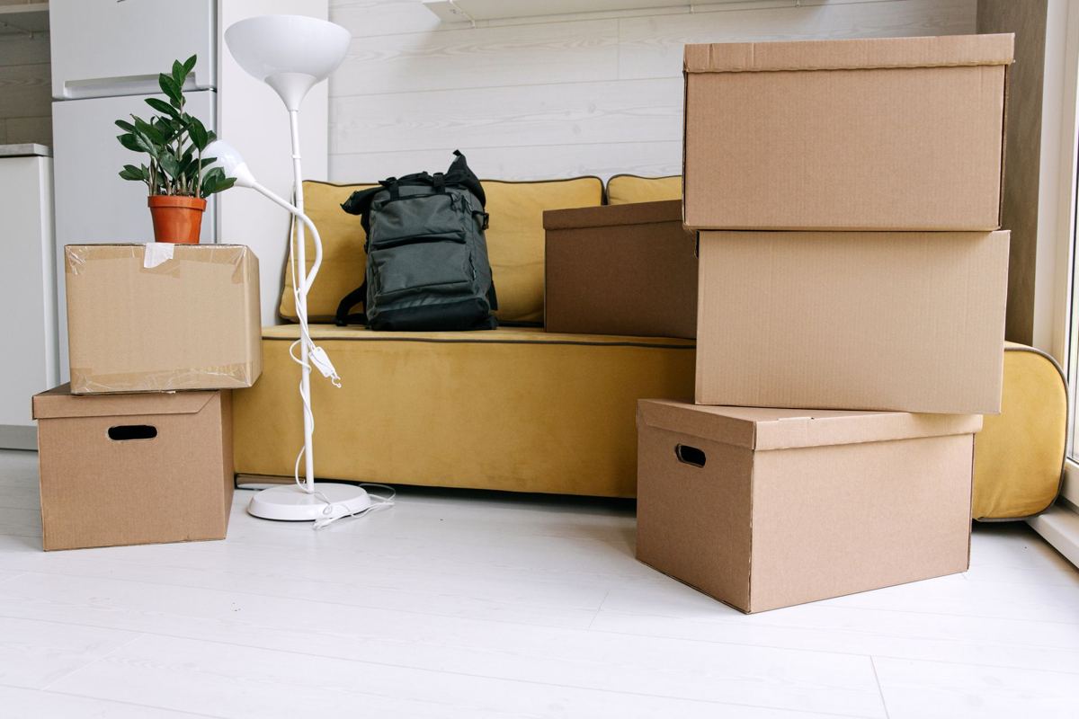 Moving boxes stacked on a sofa in a small apartment living room