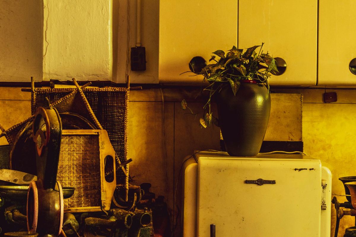 An old cream-colored refrigerator surrounded by worn household items