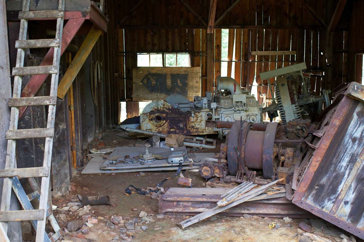 Old machinery and scrap piled inside a weathered wooden barn