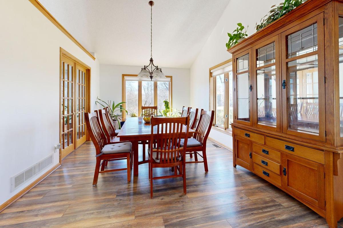 A wood dining table with slat-back chairs beside a large glass-front china hutch