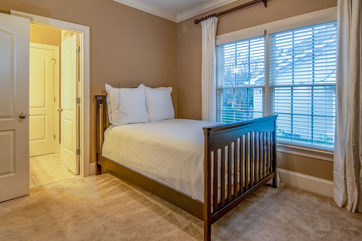 A bedroom with open floor space between the bed and the window