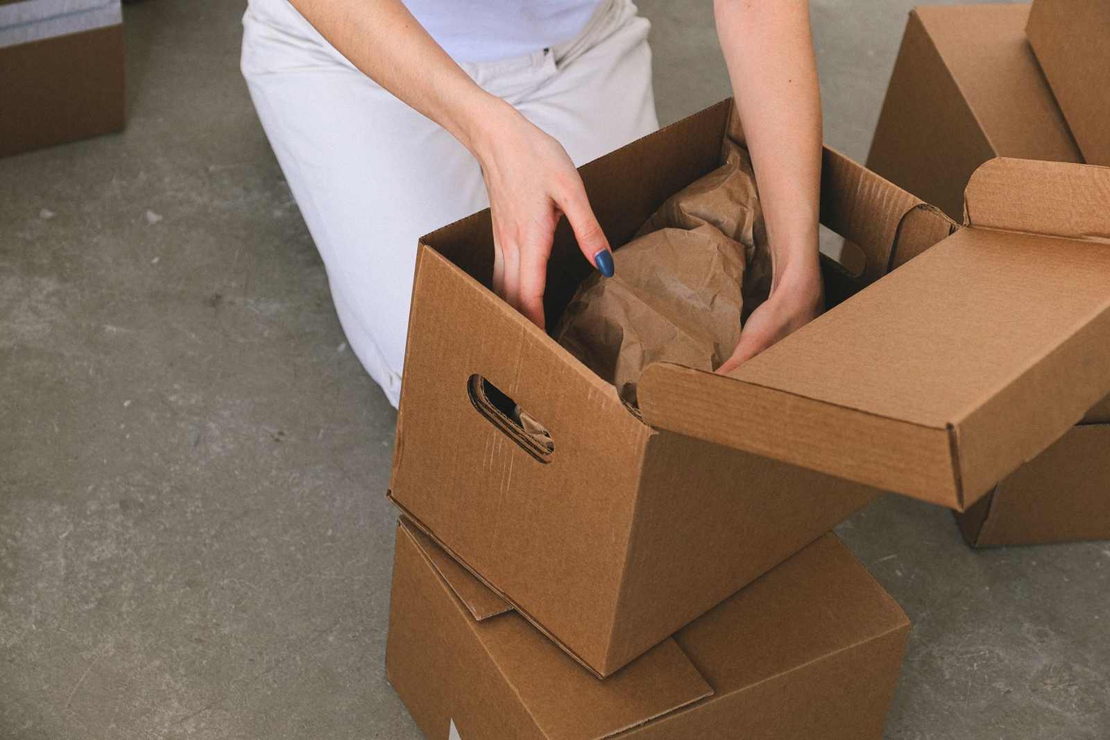 Hands packing wrapped belongings into a cardboard box while clearing a senior living apartment