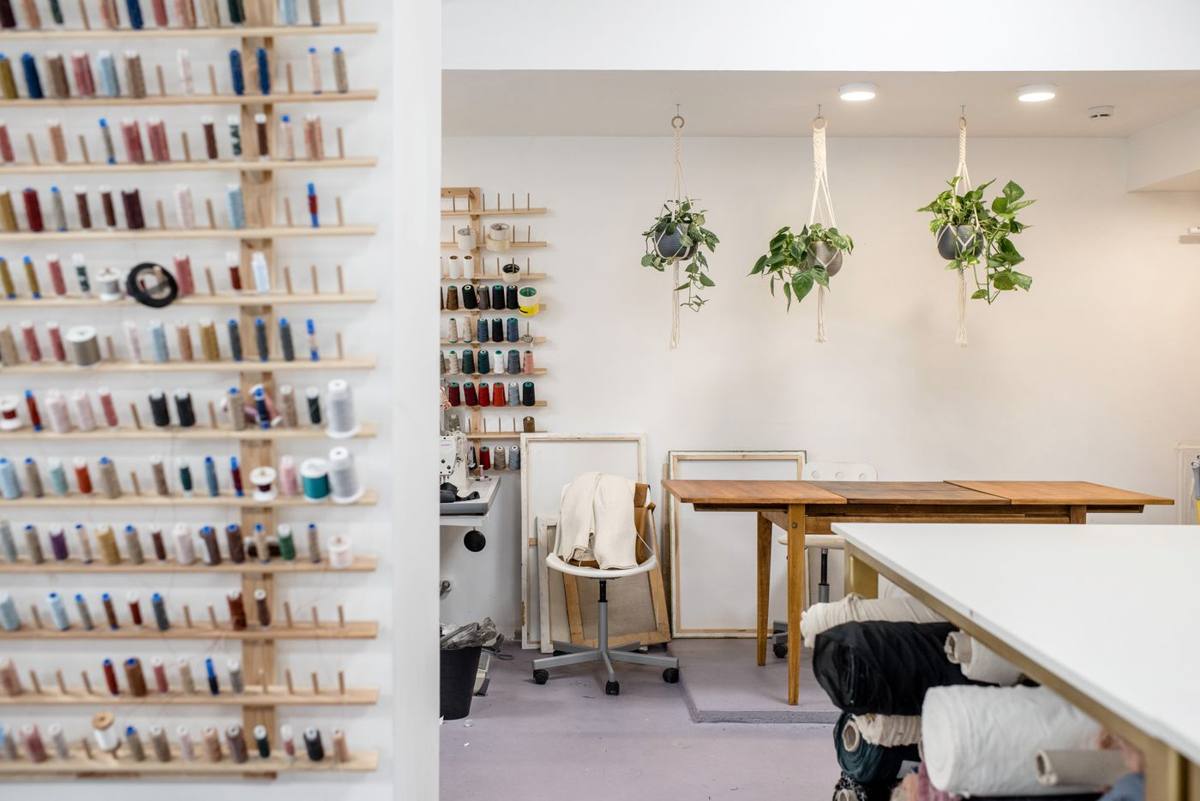 A home sewing room with thread racks, a cutting table and rolls of fabric