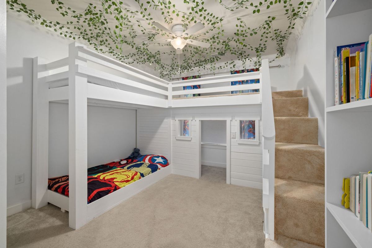 A white loft bunk bed with stairs in a child's bedroom