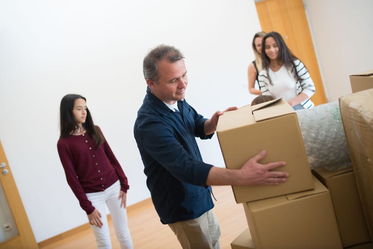 A father packing moving boxes while family members help
