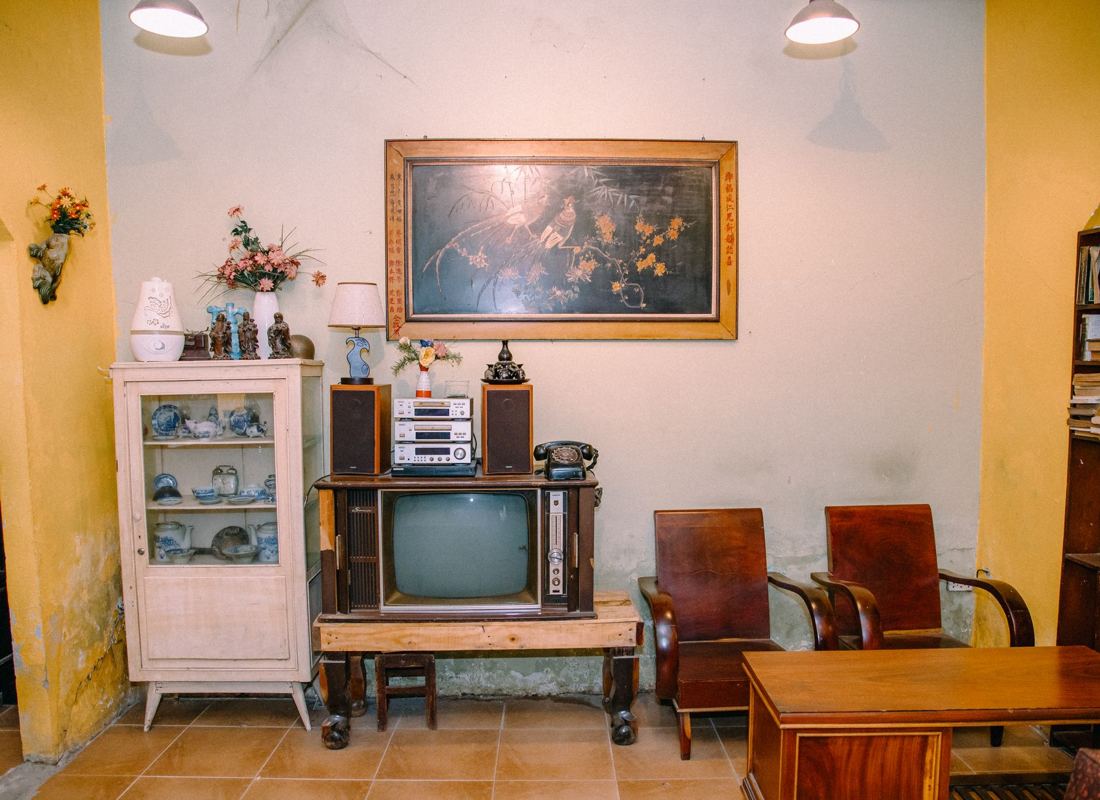 A room of older furniture with a framed painting and a vintage television
