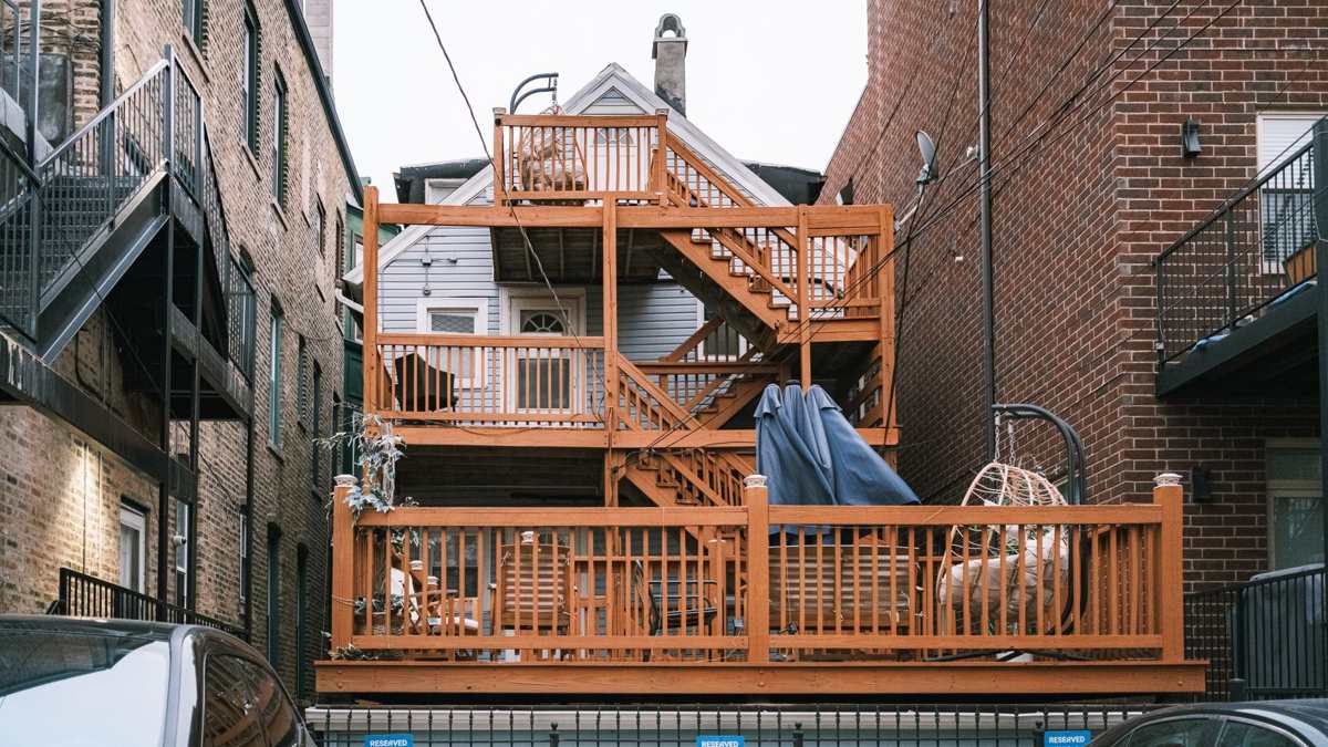 A multi-level wooden deck built onto the back of a brick house