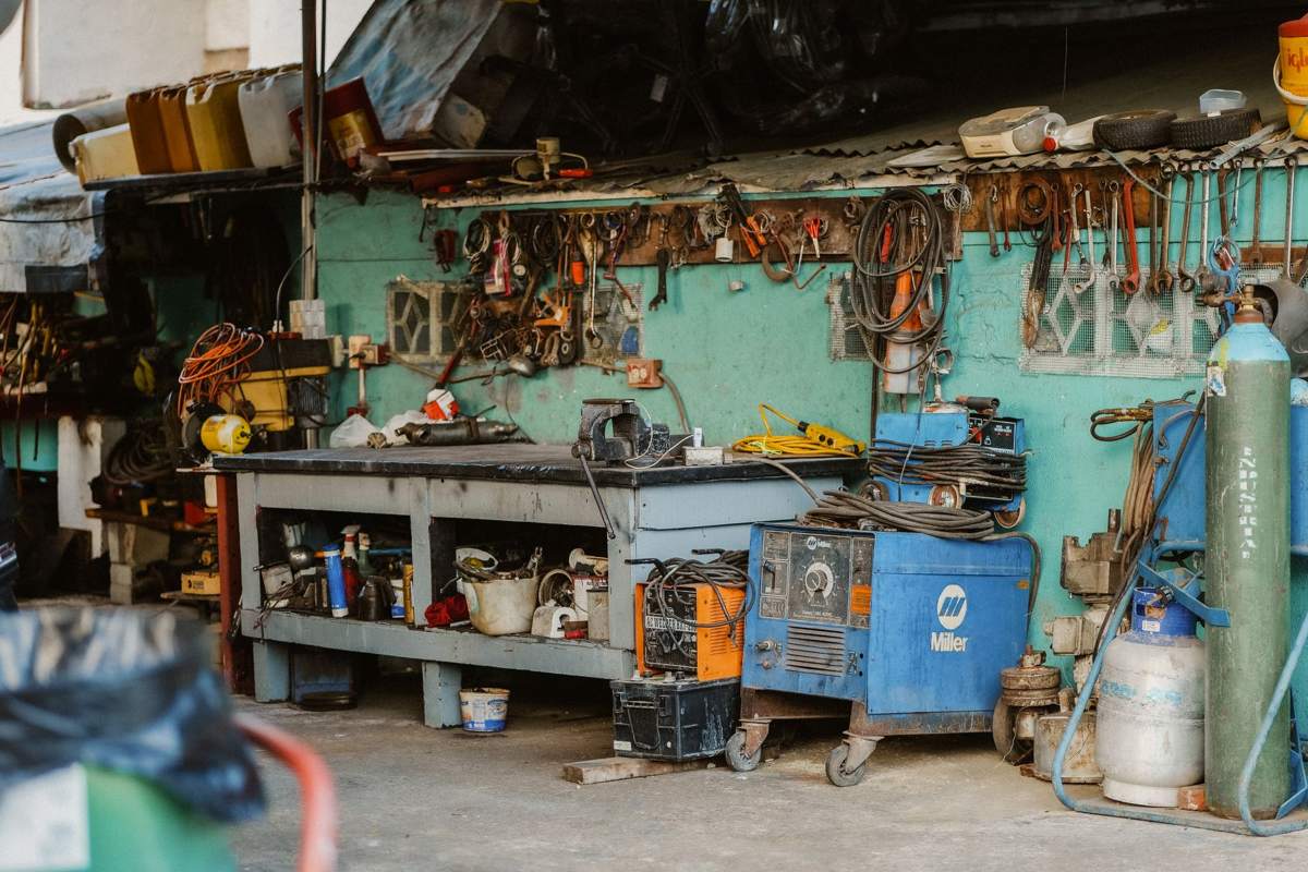 A crowded workbench under a wall of hanging tools