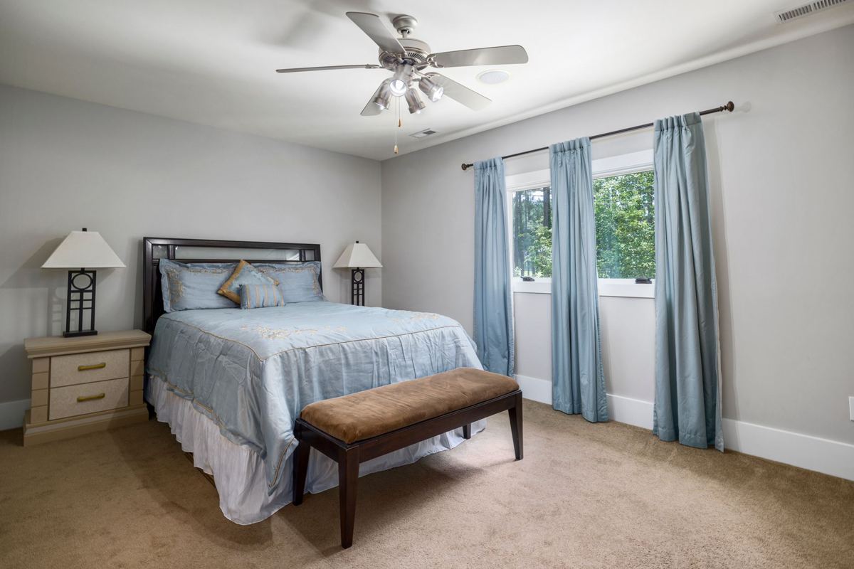 A guest bedroom with a made bed and a bench at its foot