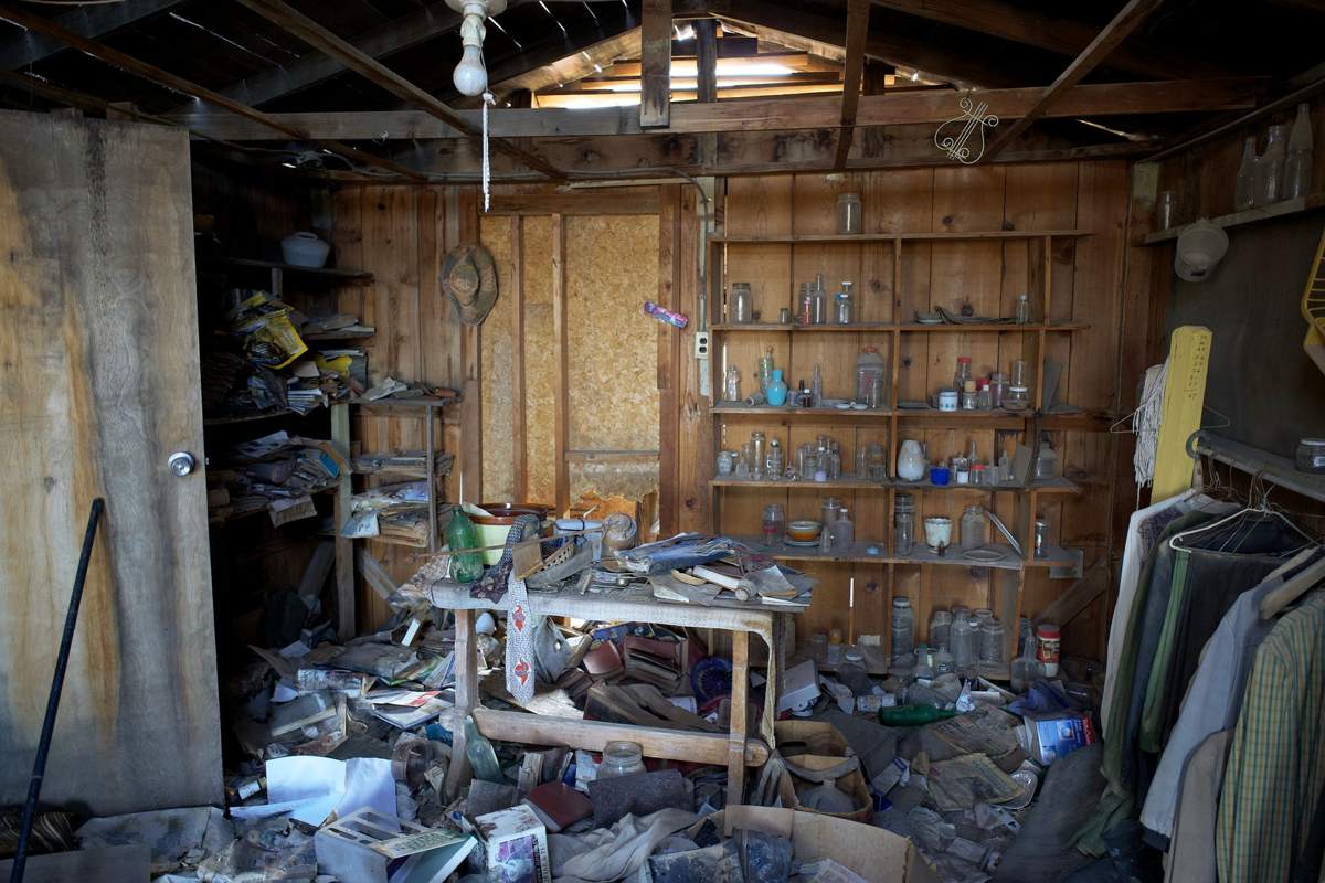 A room piled with belongings, boxes and debris