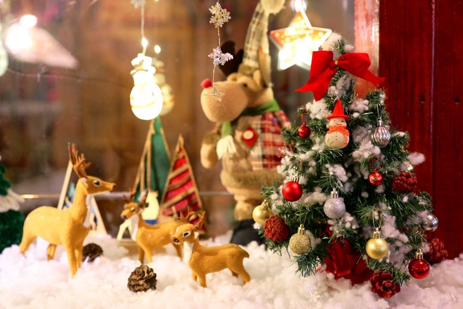A small artificial Christmas tree, reindeer figures and light-up ornaments in a holiday display