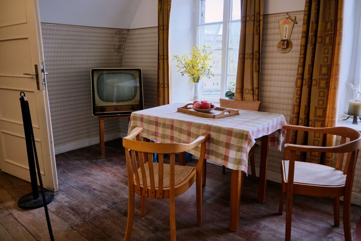 A dining table, chairs and an old television in an older home