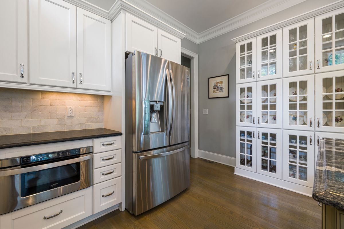 A kitchen with white cabinets and a stainless refrigerator, the pieces a remodel replaces