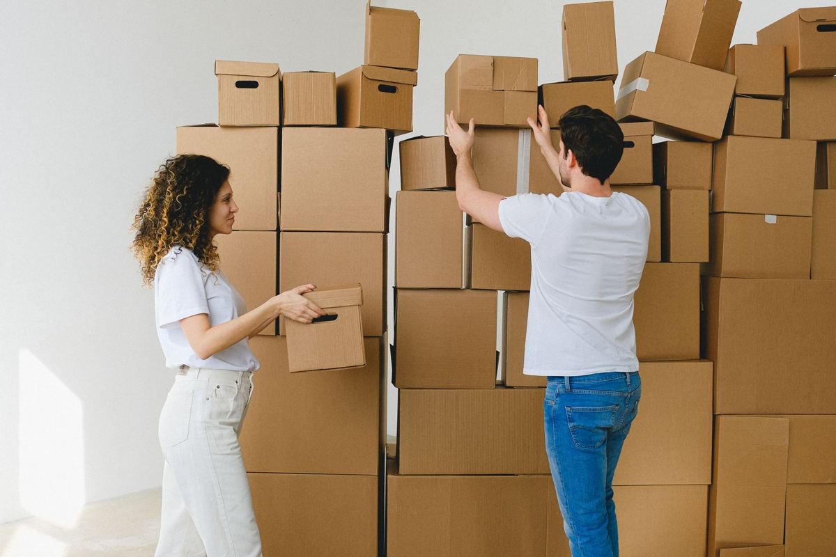 A couple stacking a wall of cardboard moving boxes