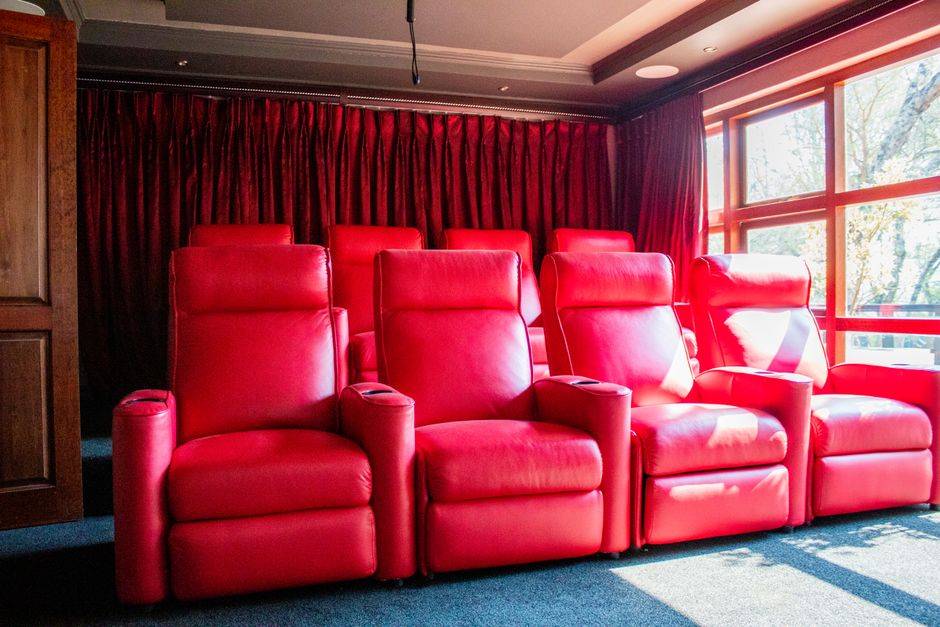 A row of red leather power recliners in a home theater room
