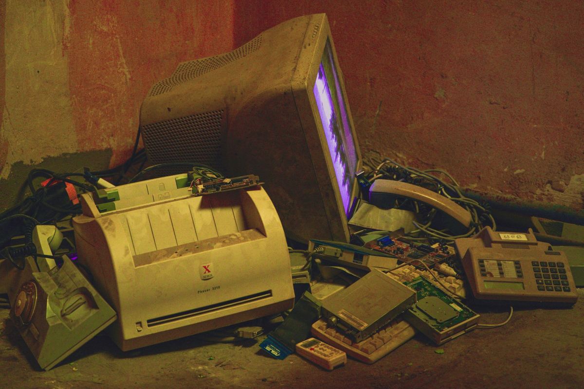 An old printer, phones and electronics left in a pile