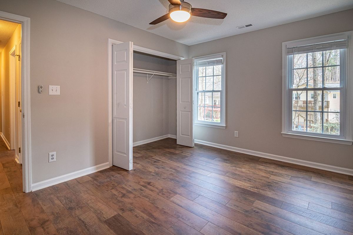 An empty rental bedroom with wood floors and an open closet