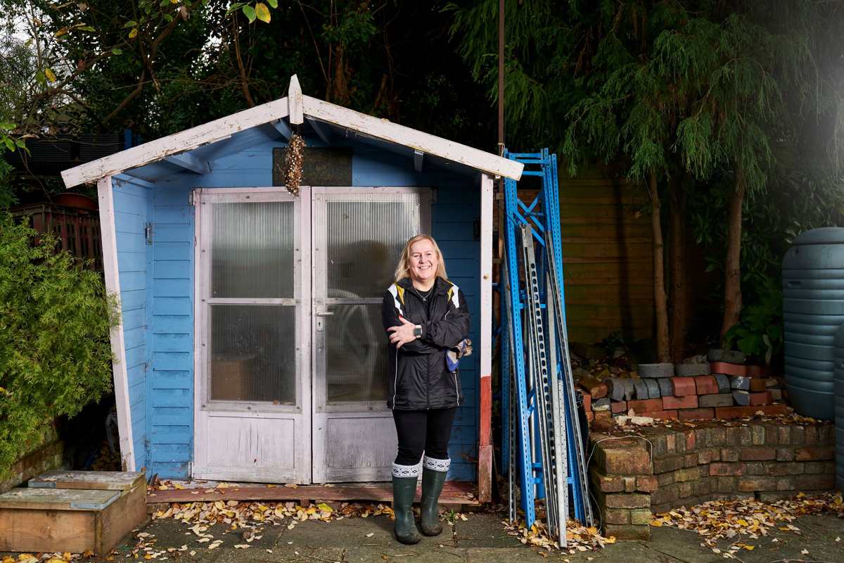 A small blue garden shed in a backyard