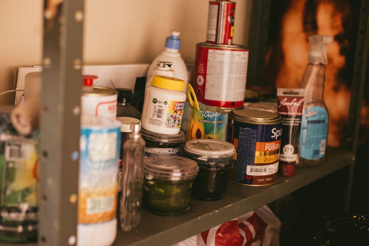 Half-used paint, cleaners and chemicals on a garage shelf