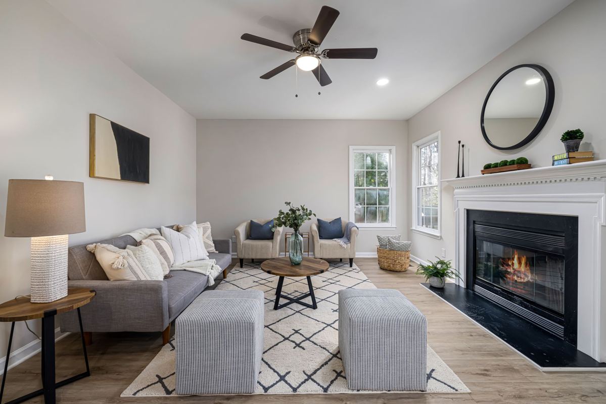 A staged living room with a fireplace and neutral furniture