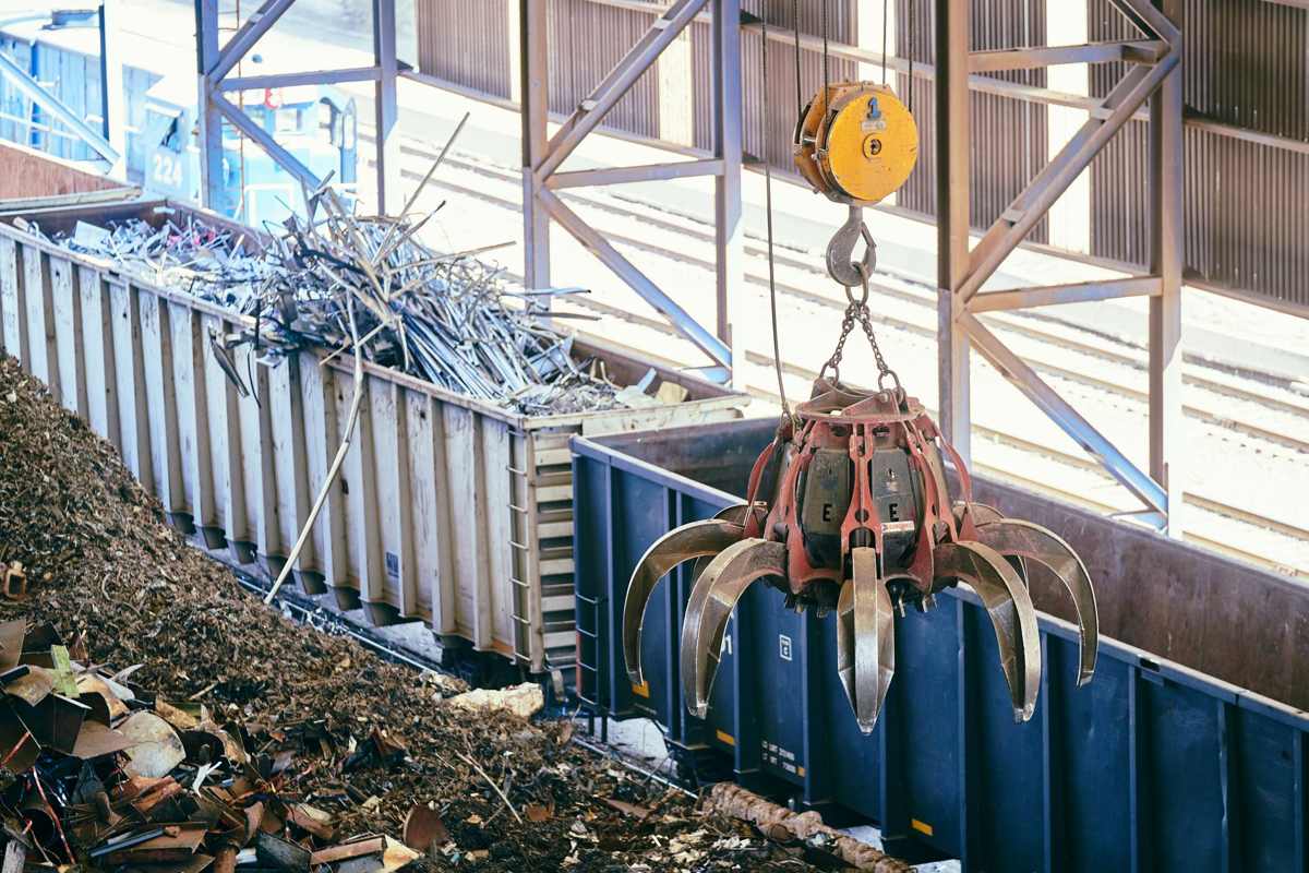A crane grapple sorting scrap metal at a recycling yard